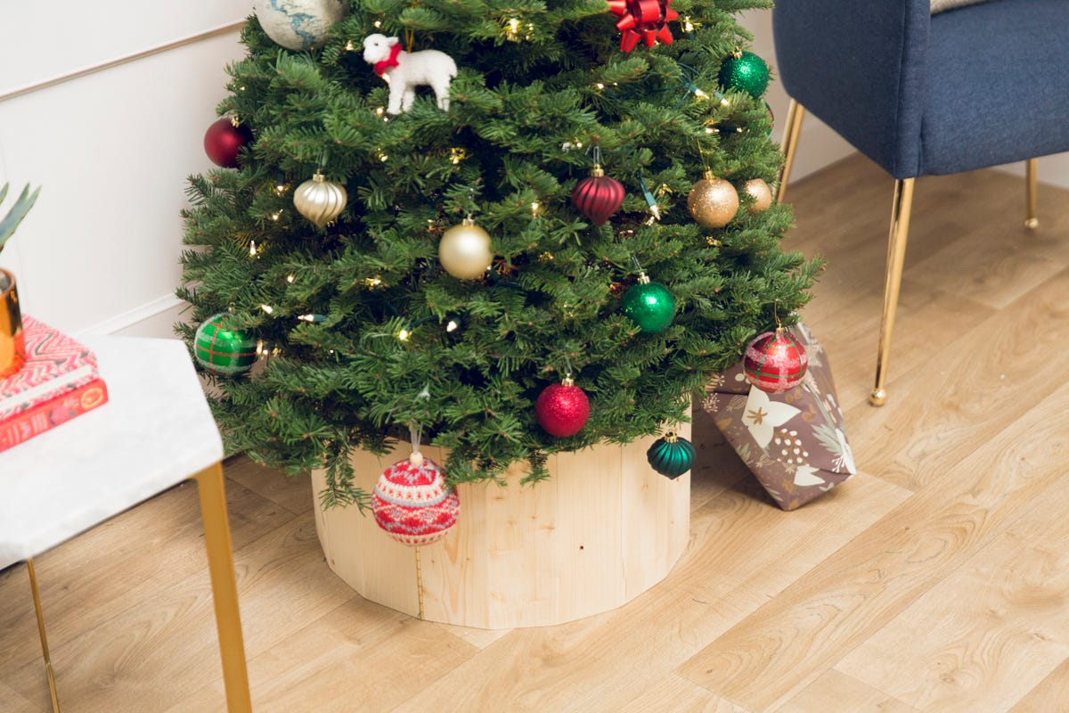 Wooden DIY entryway hall tree installed on wall, with items on top shelf and hanging from hooks. 