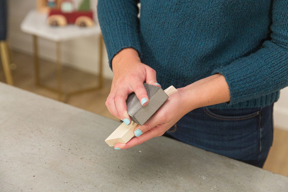 Holding white wood pieces together in a rectangle to form inside frame. 