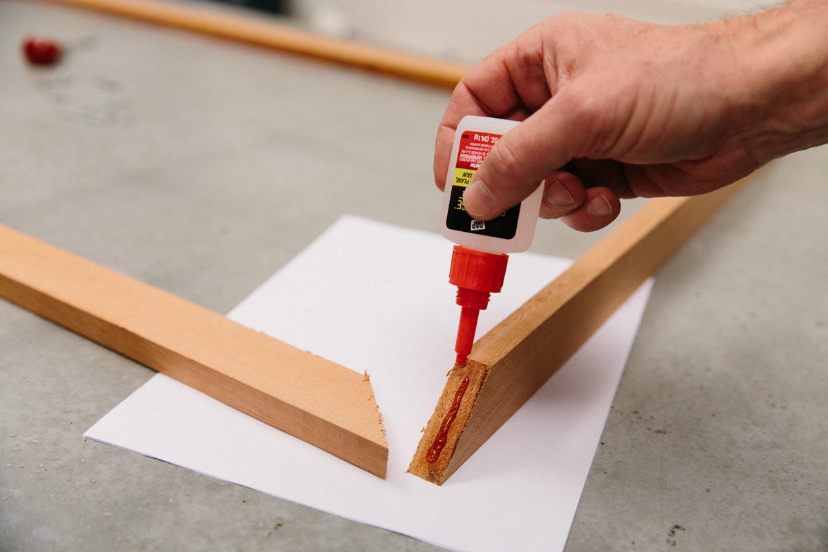 Applying rapid-set exterior glue to cut edges of DIY decorative utility screen frame boards.
