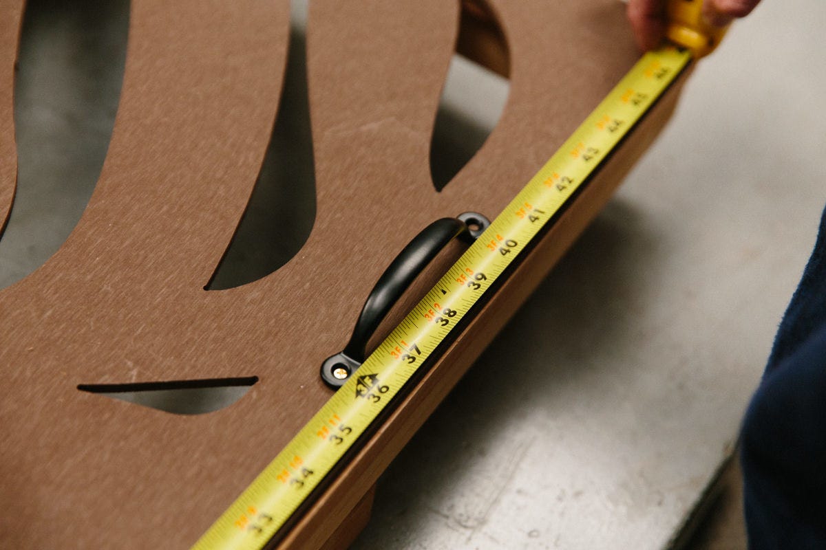 Measuring placement of handle on DIY decorative utility screen assembly with measuring tape.
