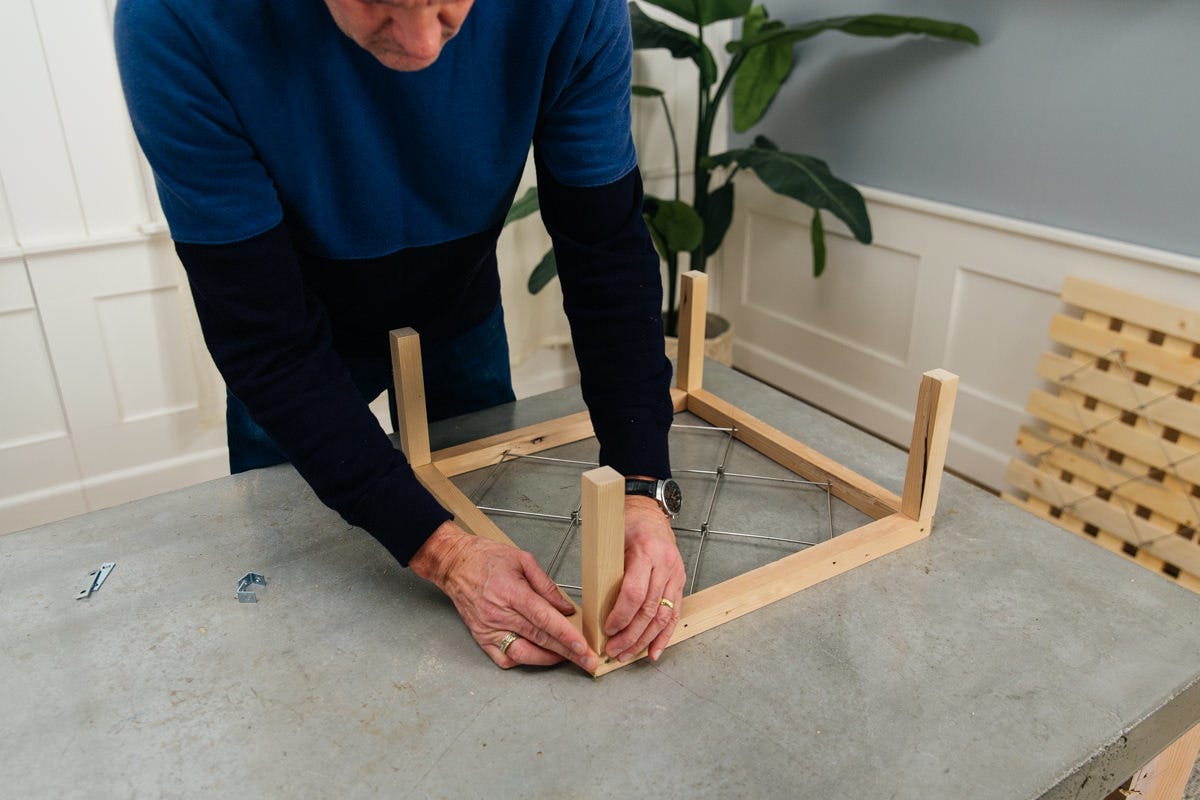 Placing legs on DIY wine rack trellis assembly.
