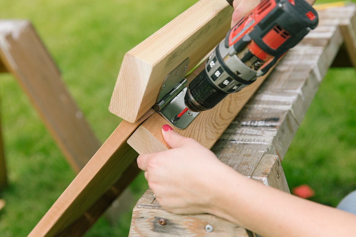 Drilling to attach hinge to base of DIY wooden lounge chair back assembly.