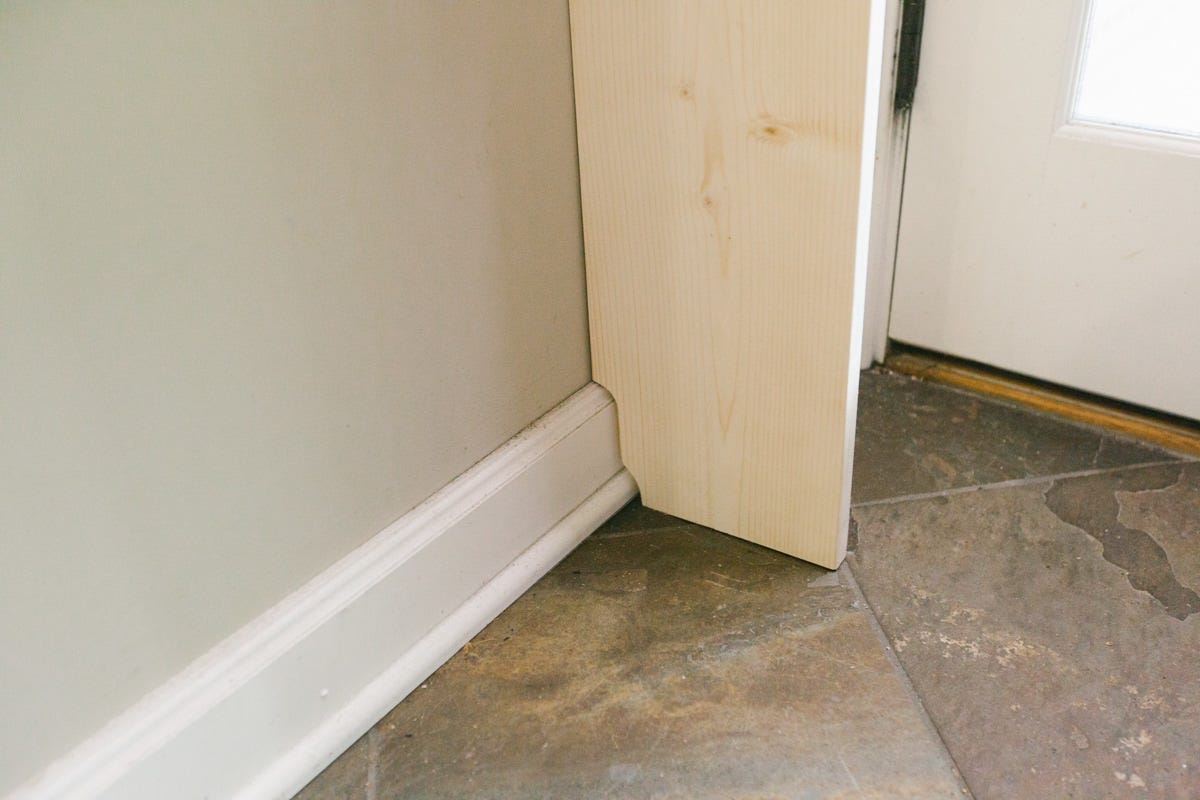 Board with notch set against wall and moulding. 