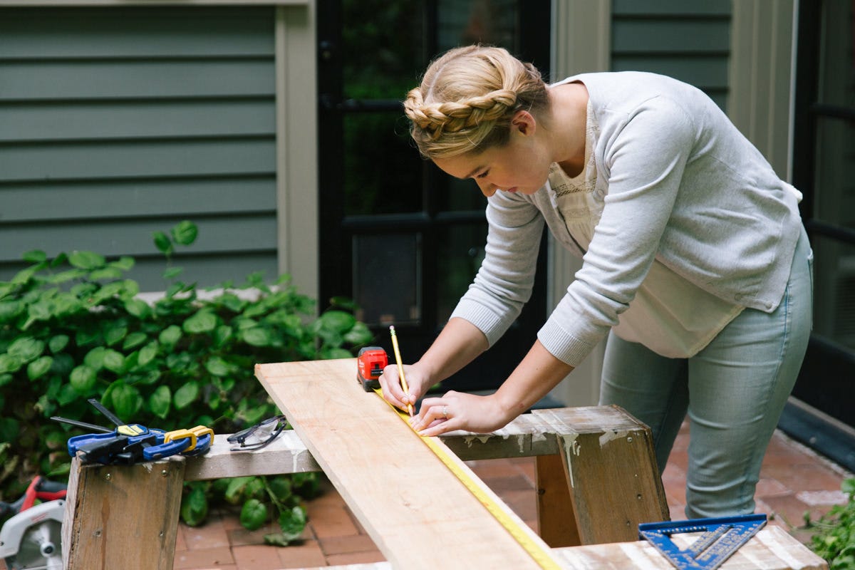 Measuring and marking board balanced on sawhorse with measuring tape and pencil.