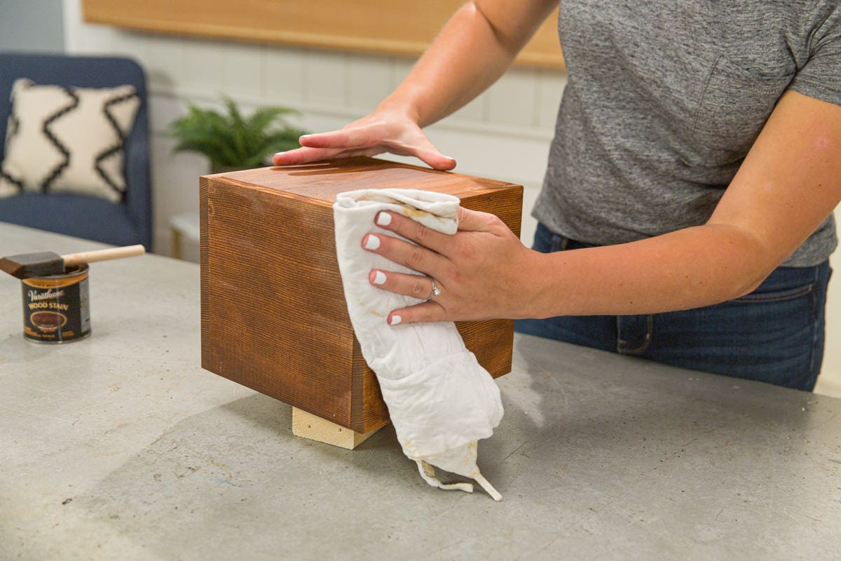 Wiping excess stain off of DIY wooden Halloween treasure box with rag.