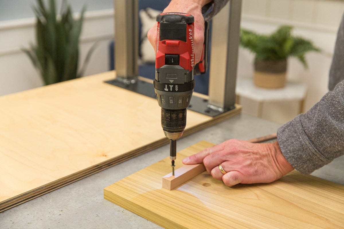 Driving bolt with power drill to attach wood scrap to poplar shelf. 